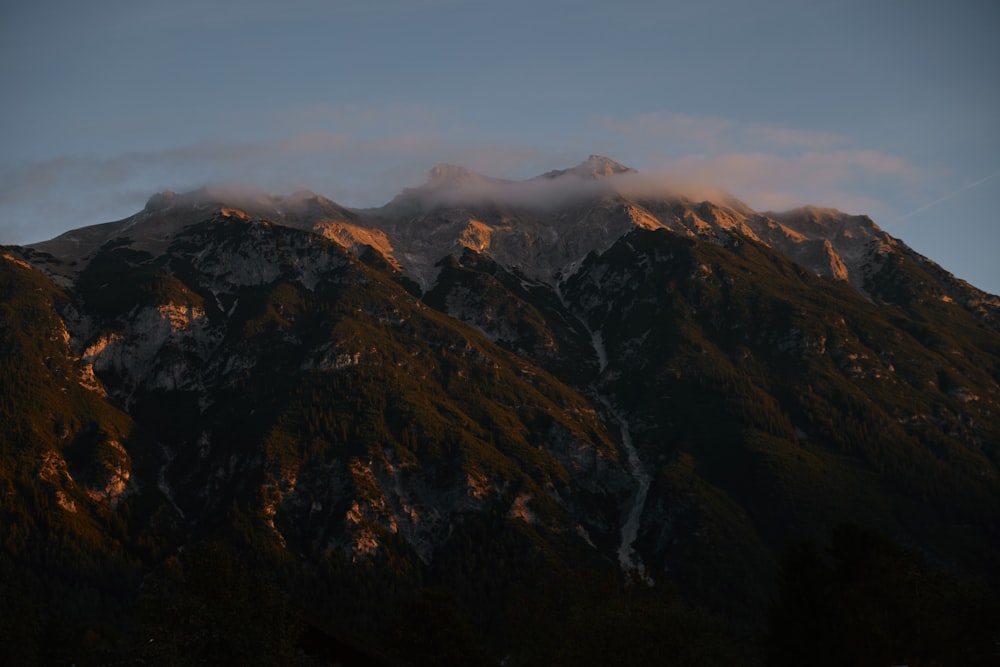 a mountain covered in snow and clouds under a blue sky