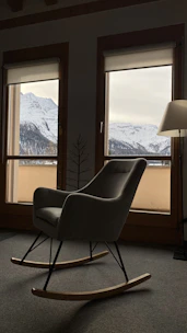 A cozy wooden armchair with soft wool cushions set beside a snow-covered window.