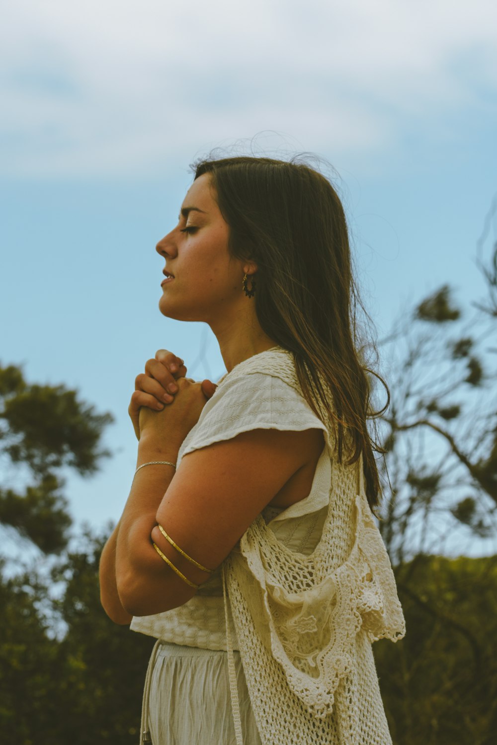 a woman standing with her hands folded in prayer