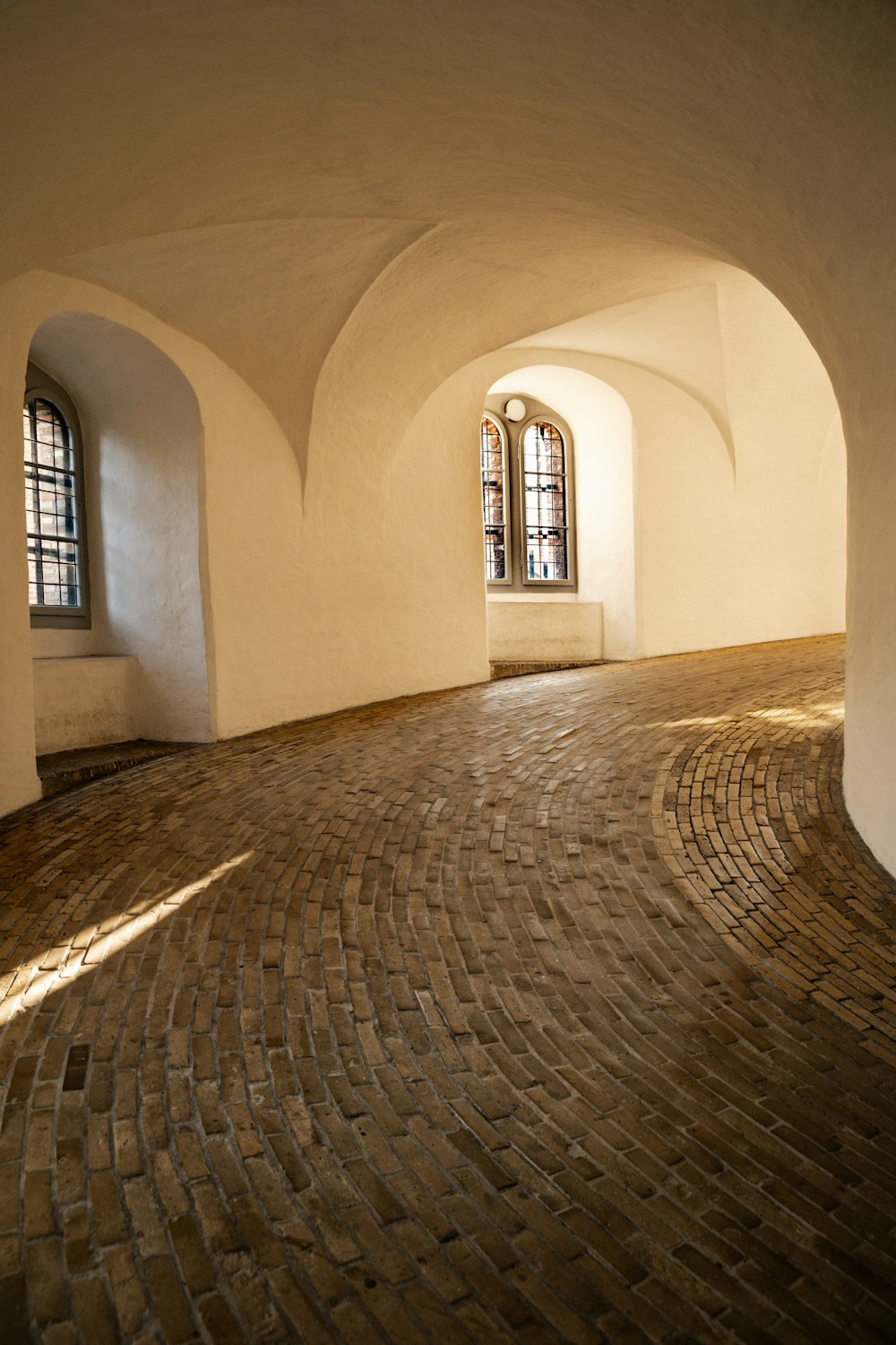 una habitación con suelo de ladrillo y ventanas arqueadas