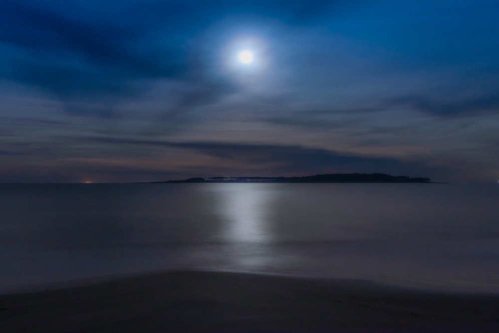 a full moon is seen over the ocean