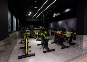 Young people cycling energetically in a spinning class with bright, dynamic lighting