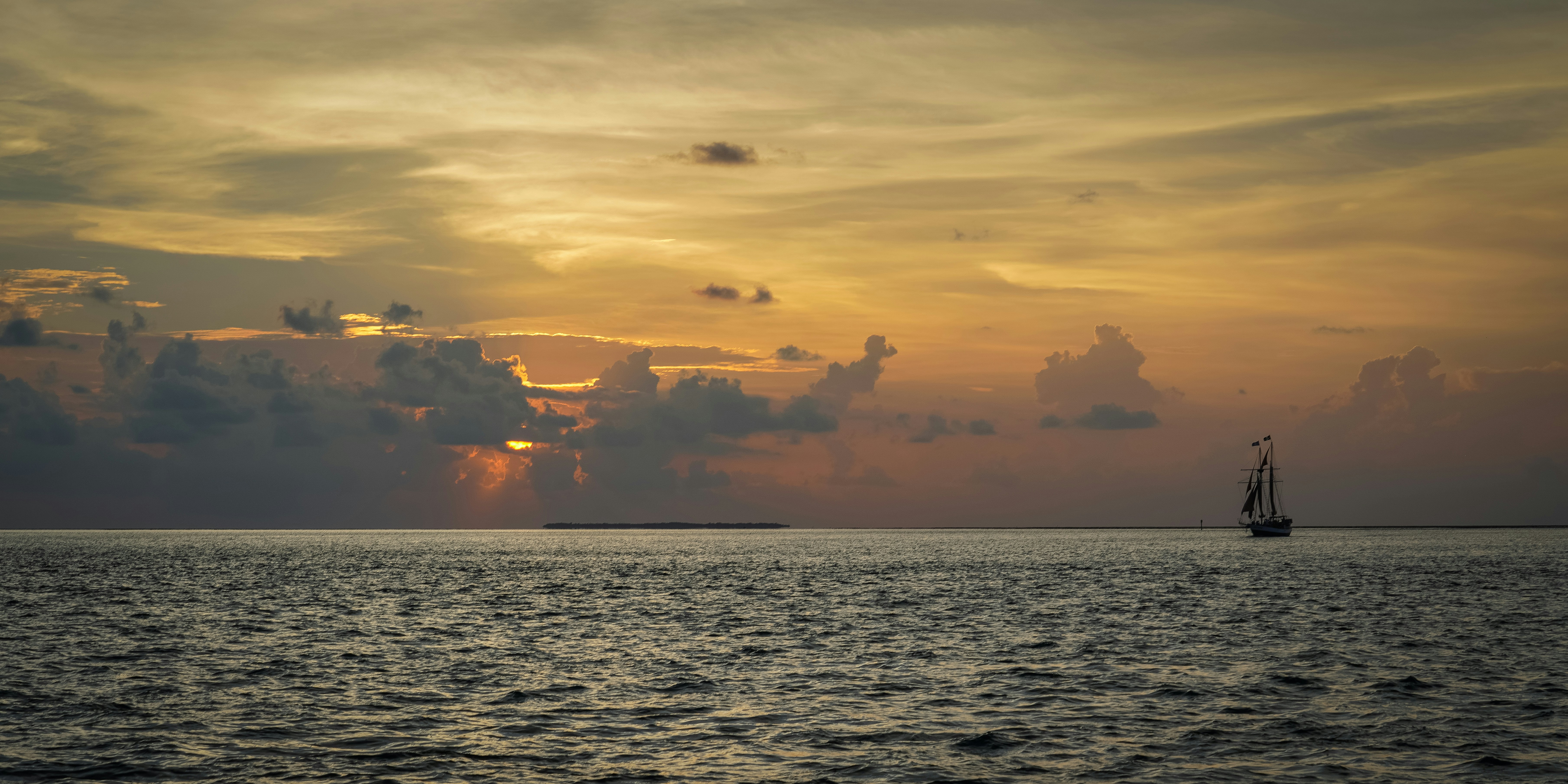 a sailboat in the ocean at sunset