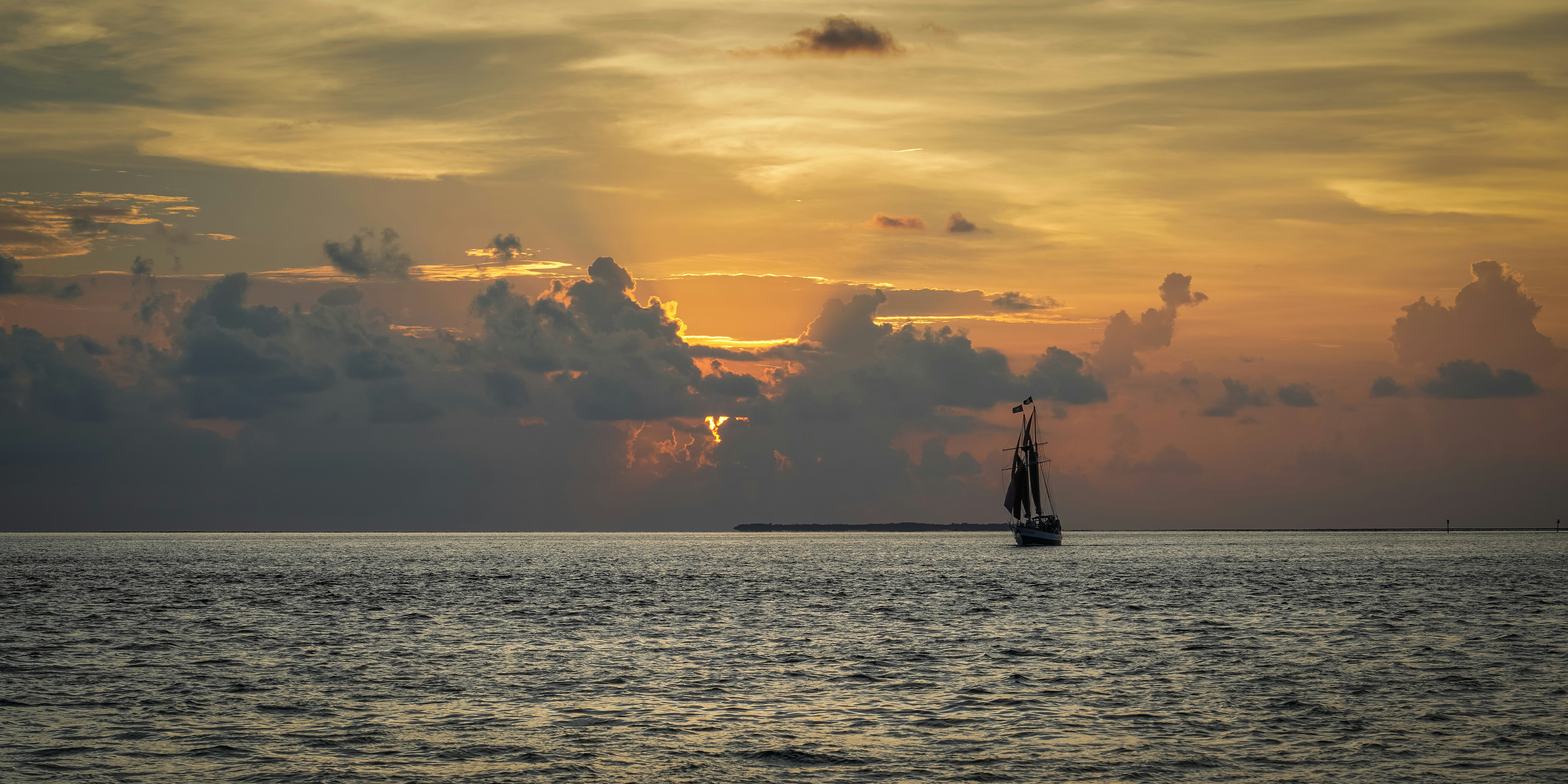 a sailboat in the ocean at sunset
