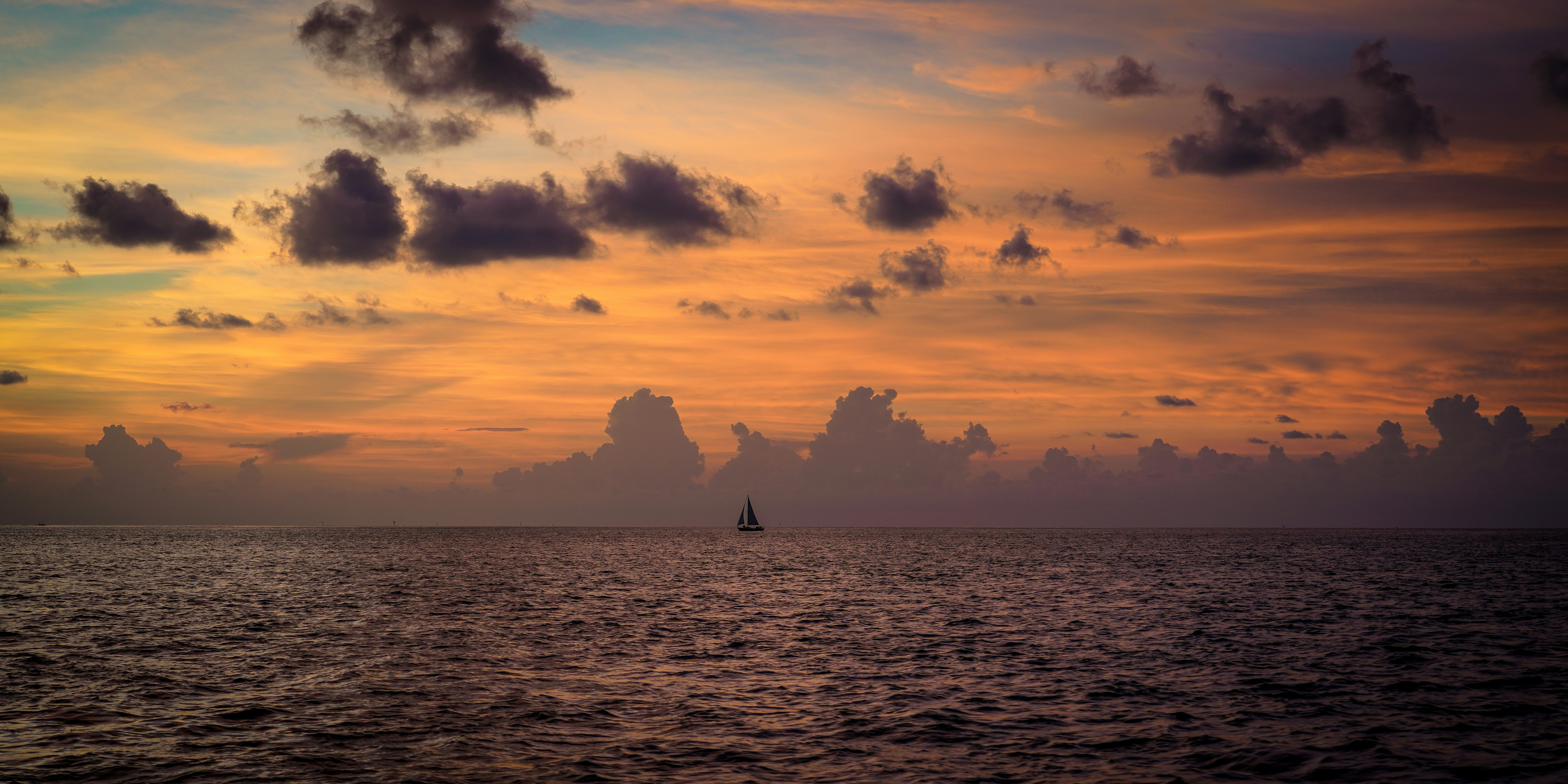 a sailboat in the ocean at sunset