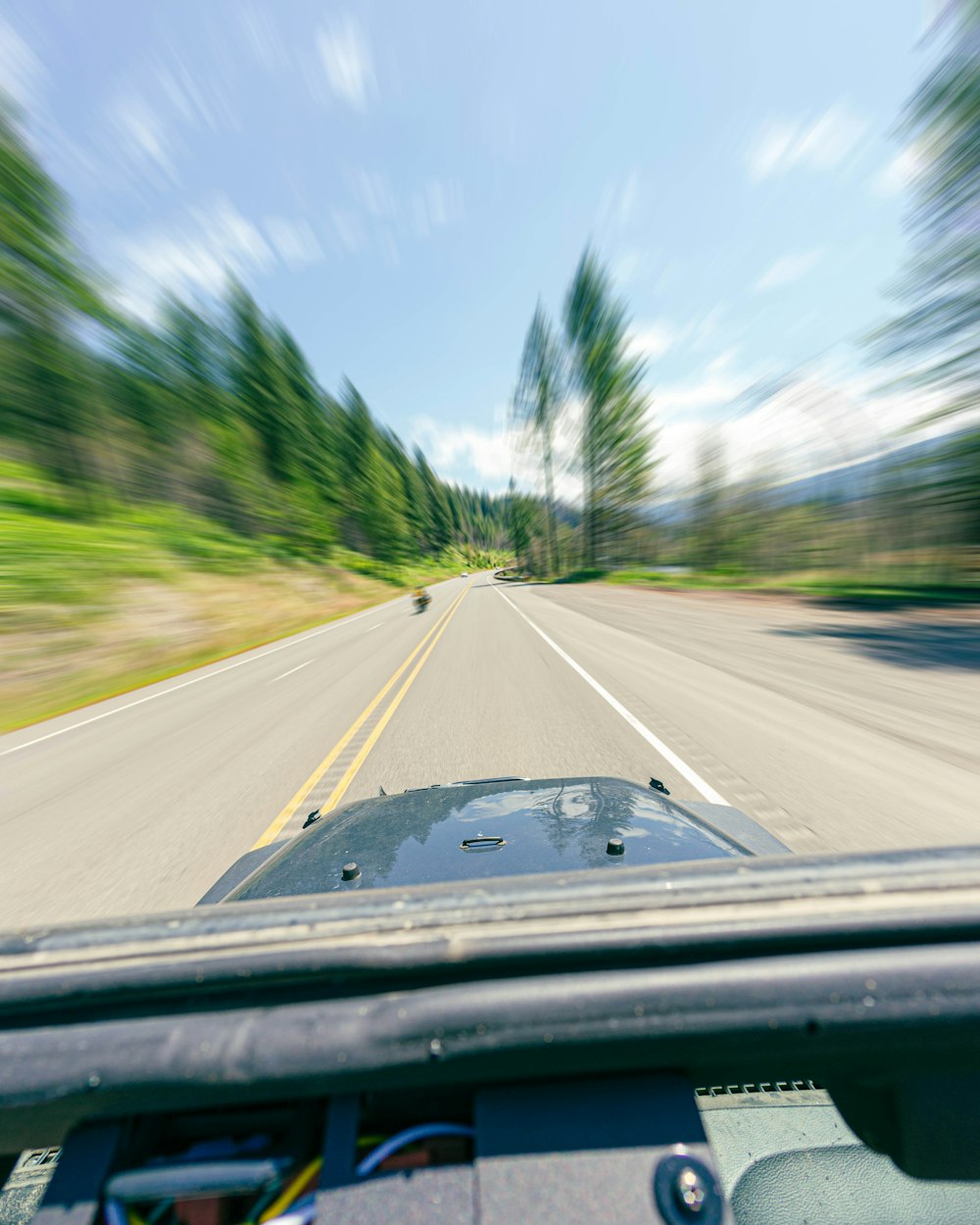 a car driving down a road next to a forest