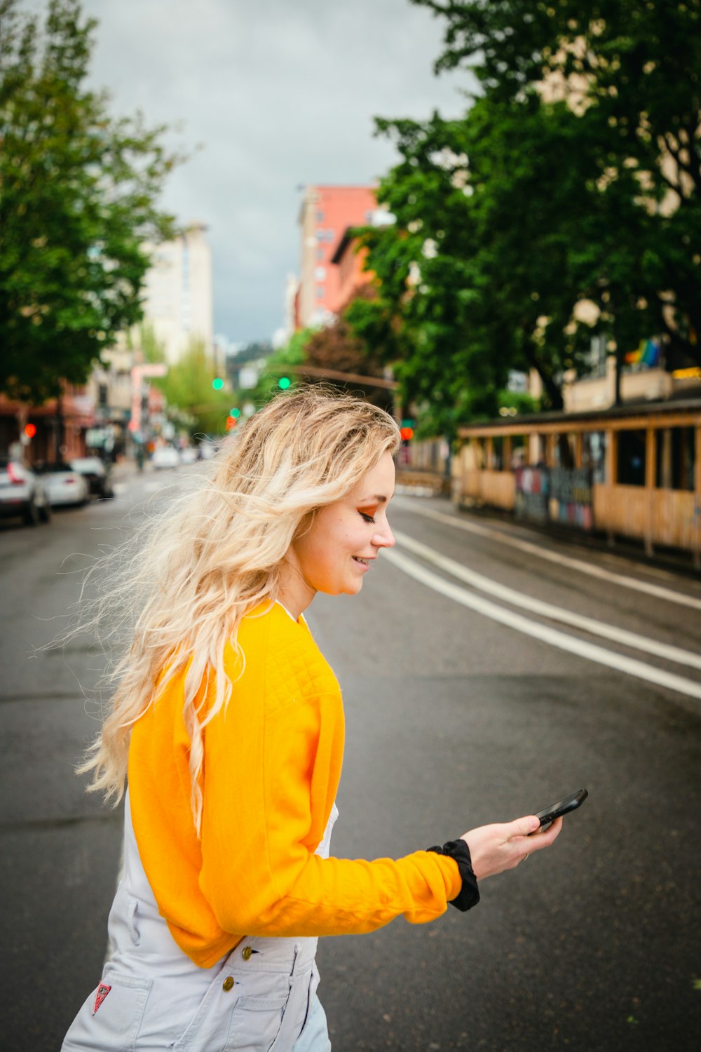 a woman walking down a street holding a cell phone