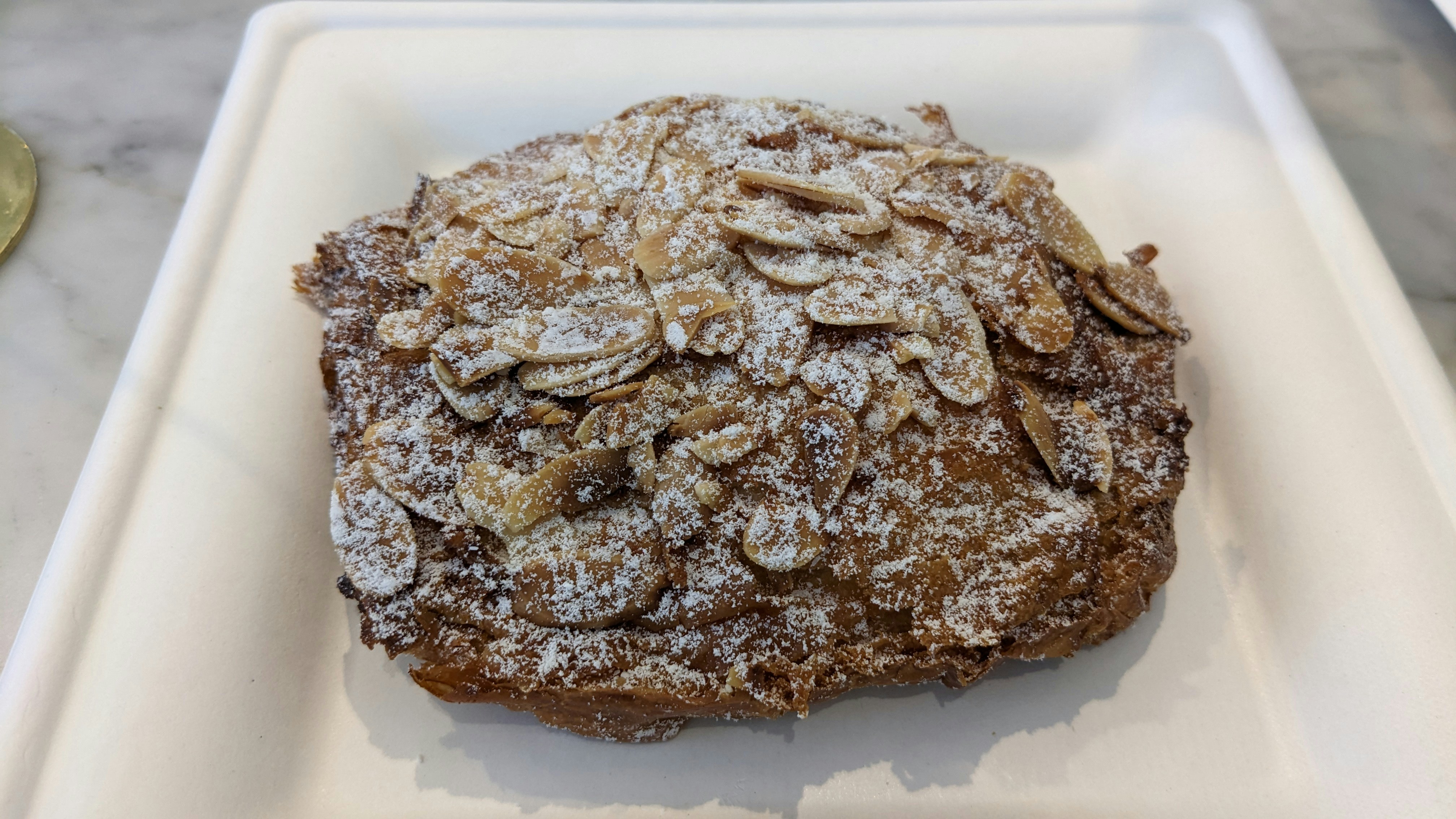 Chocolate almond croissant dusted with powdered sugar, dark chocolate filling visible