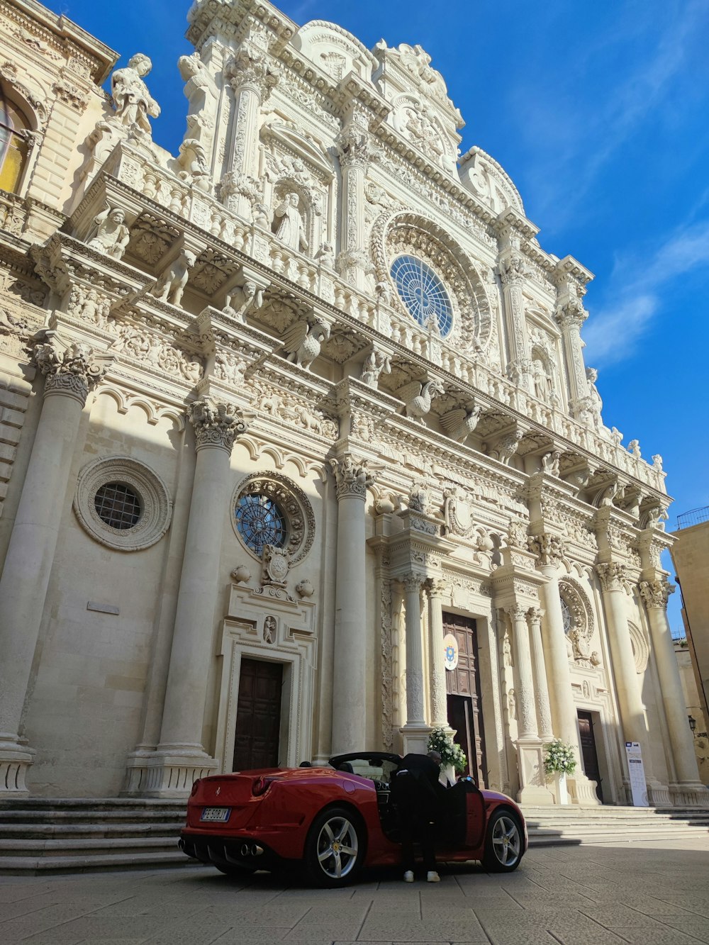 a red car parked in front of a church