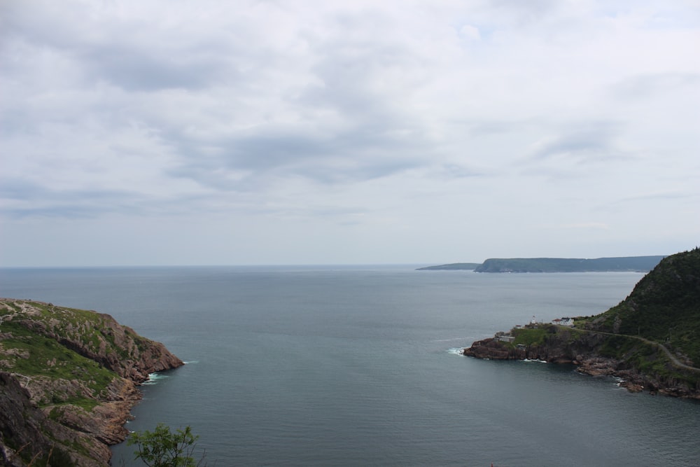 a large body of water surrounded by a lush green hillside