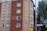 A multi-story building with a red and beige brick facade features multiple square windows. The building has a large vertical sign that reads 'Unite Students' in yellow letters. A street sign indicates 'Blackstock Street' in front of the building, and there is a tree visible on the right side.