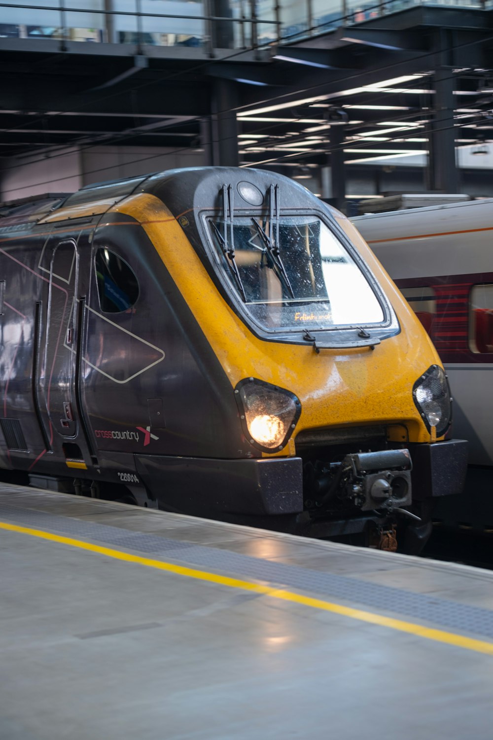 a yellow and gray train pulling into a train station