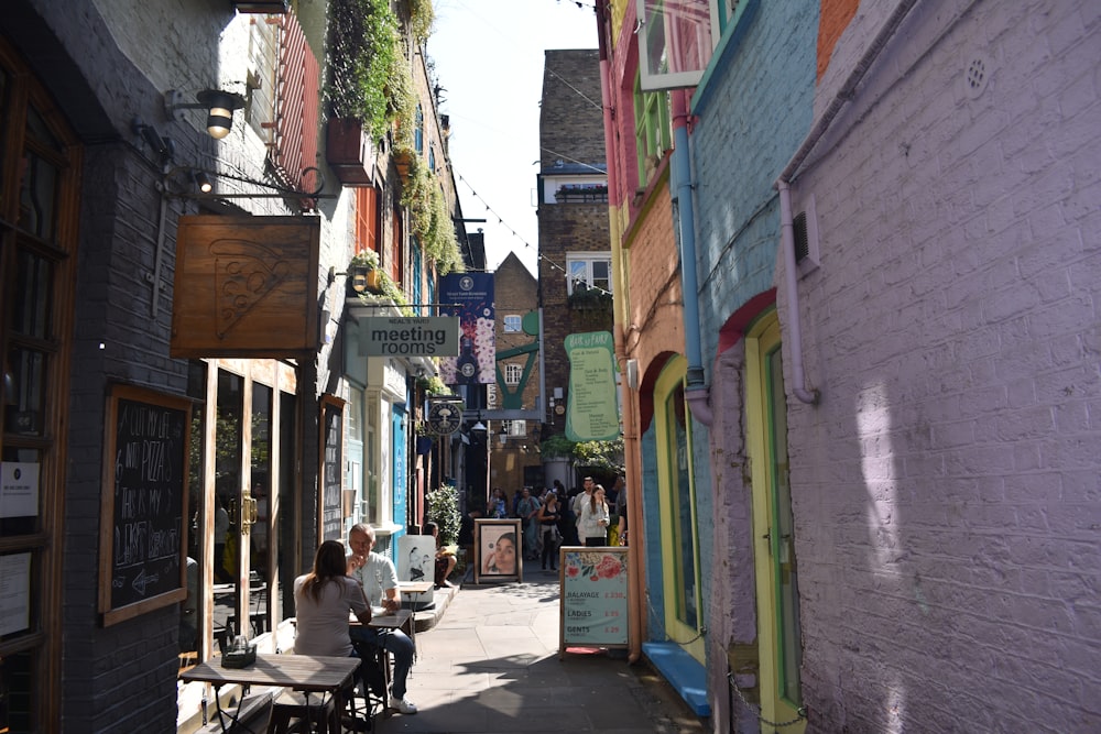 a narrow city street with people sitting at tables