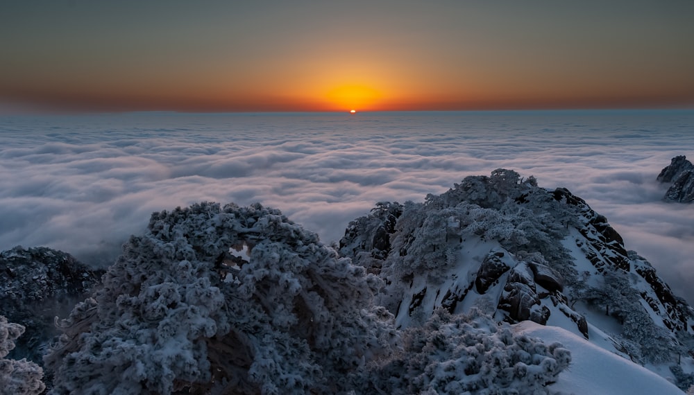 the sun is setting over the clouds in the mountains