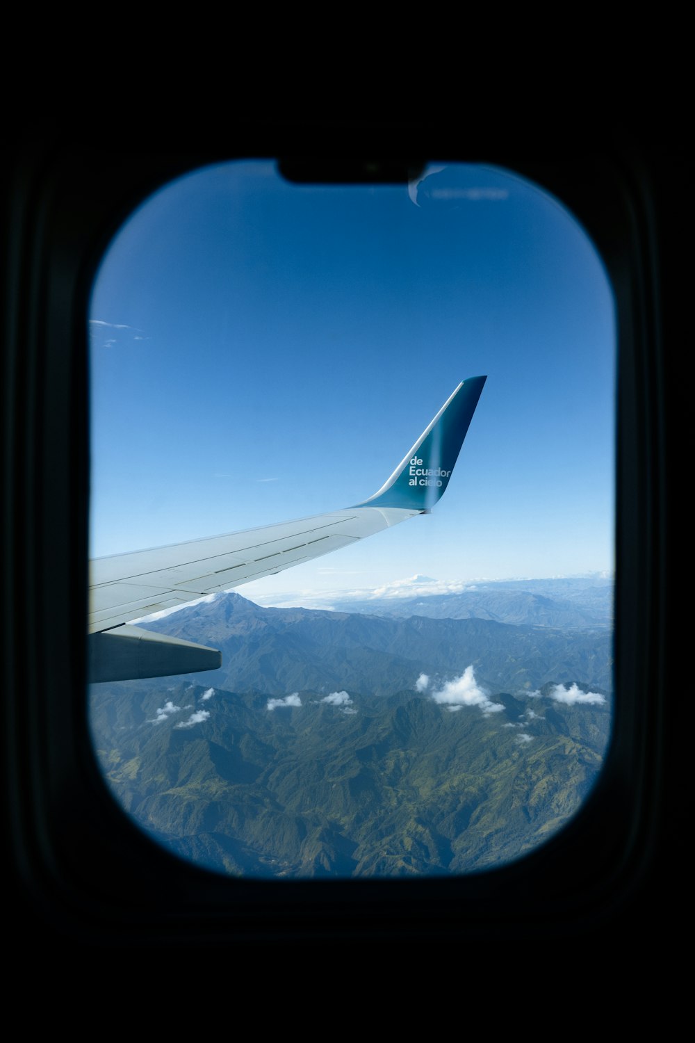 a view of the wing of an airplane as it flies over a mountain range