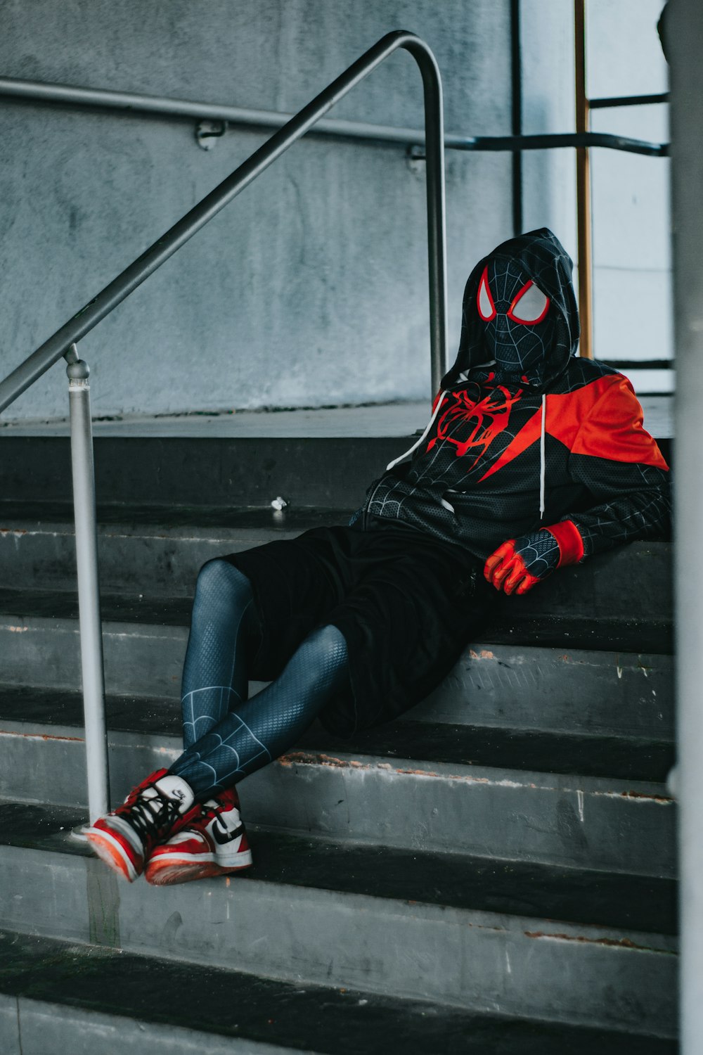 a person in a spider man costume sitting on some stairs