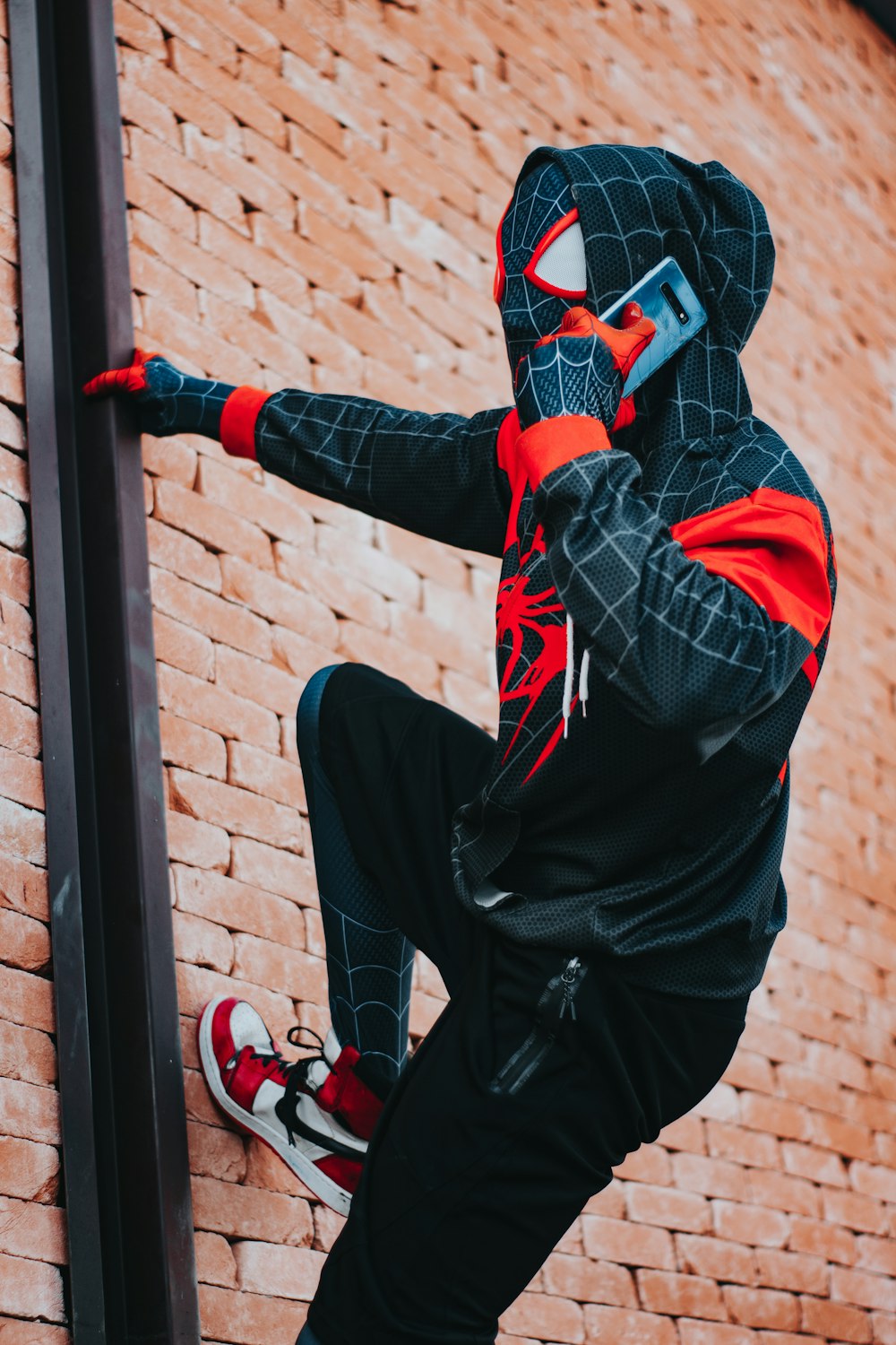 a man in a spider suit is climbing a brick wall
