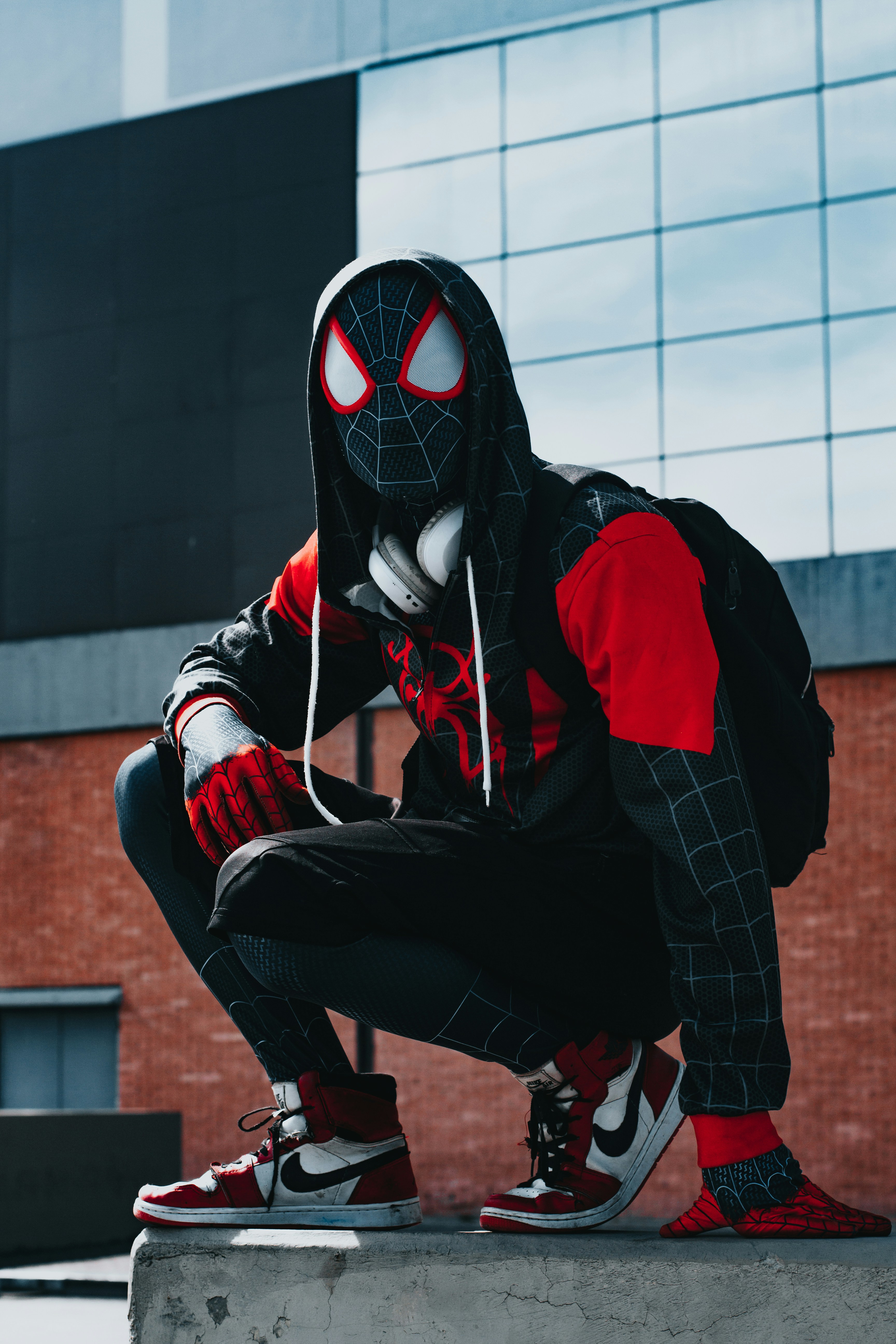 a man in a spider suit is sitting on a ledge