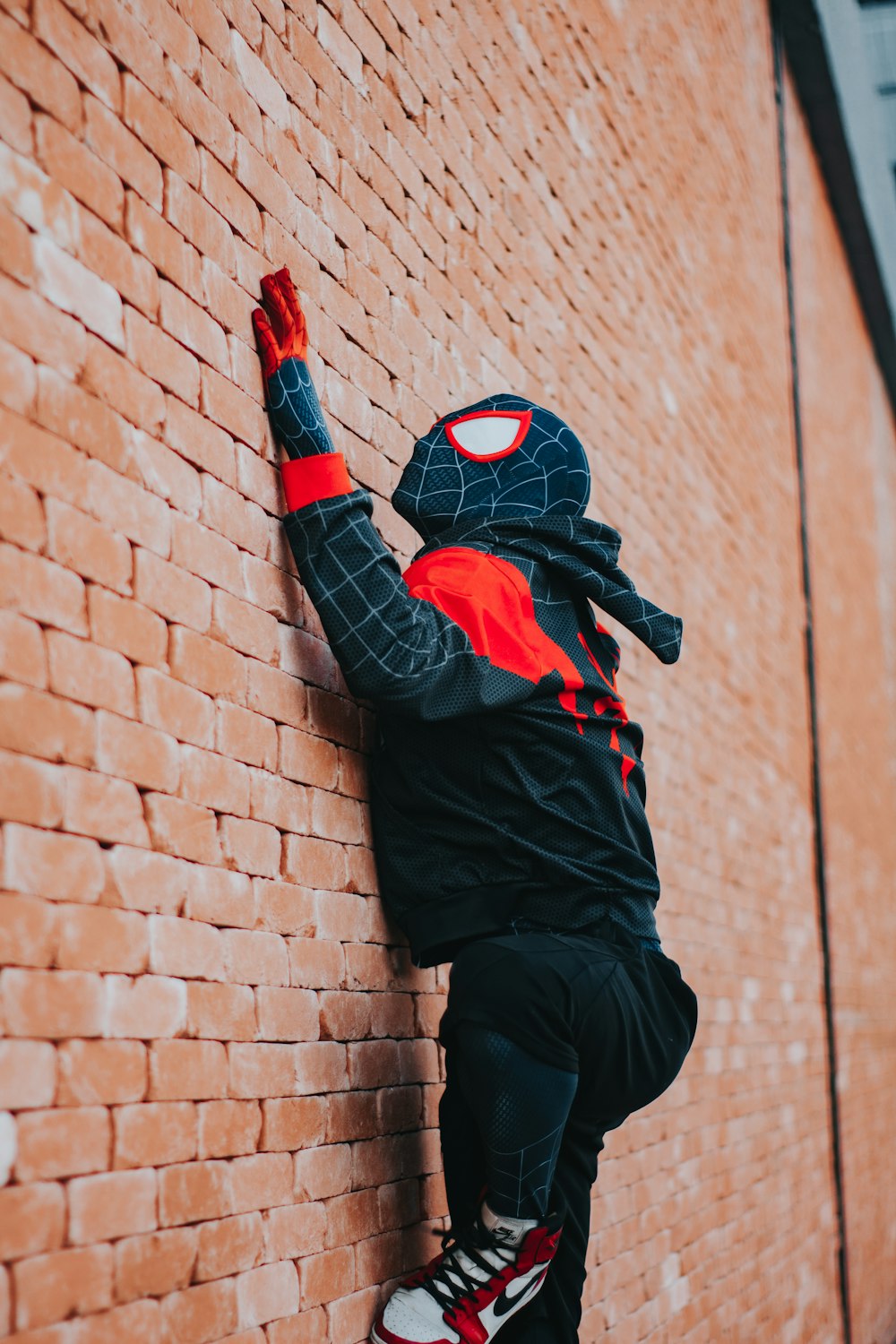 a man in a spider suit climbing up a brick wall