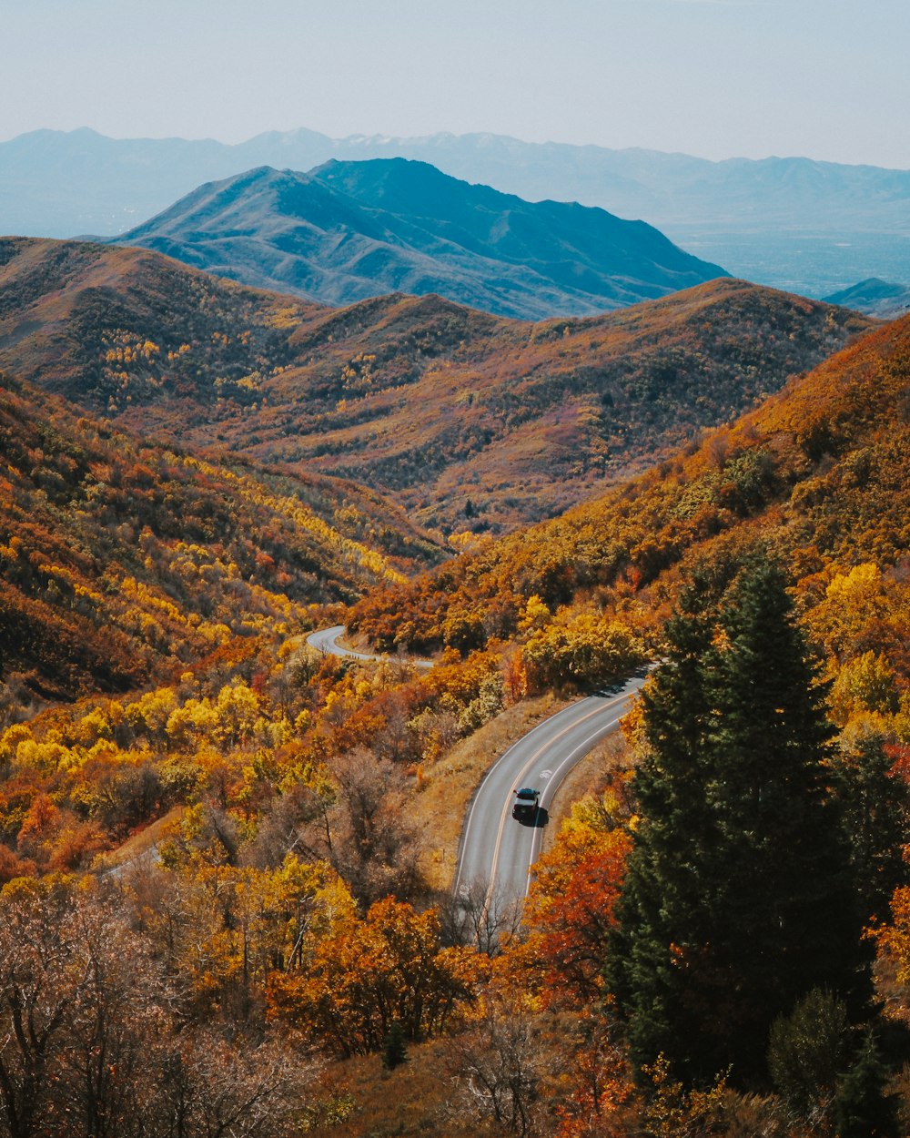 a car driving down a road surrounded by mountains