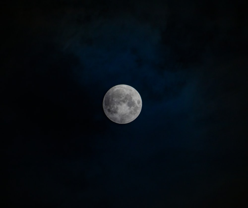 a full moon is seen in the dark sky