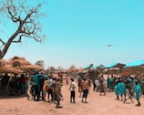 An outdoor event with drones flying above a large crowd at dusk.