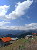 Sunset view over the rolling hills of the Quindío coffee region with traditional wooden cabins in the foreground.