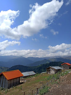 Sunset view over the rolling hills of the Quindío coffee region with traditional wooden cabins in the foreground.