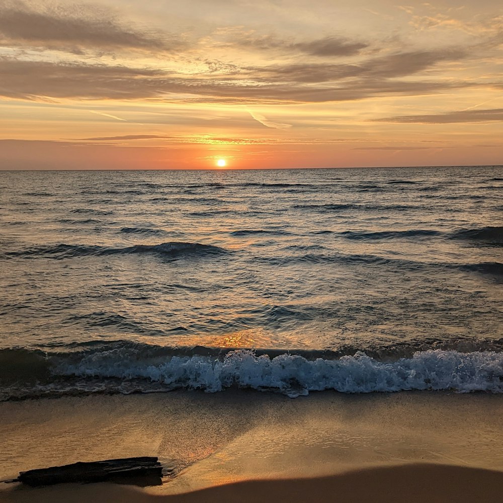 the sun is setting over the ocean on the beach