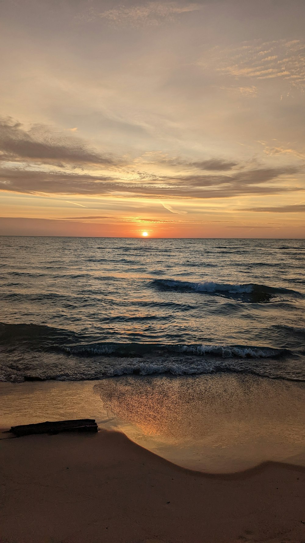 the sun is setting over the ocean on the beach