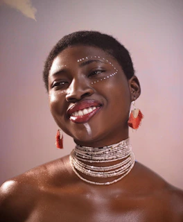 A woman wearing bold, feminine polymer clay earrings, smiling softly in natural light