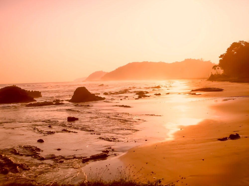 the sun is setting over the water at the beach