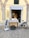 A storefront with a bicycle cart in front, displaying the name 'IMPASTI 4.1'. Two baskets filled with bread are placed on a covered table in front of the shop. A chalkboard sign on a stand beside the cart advertises pizza. The building features stone arches and a light yellow exterior.