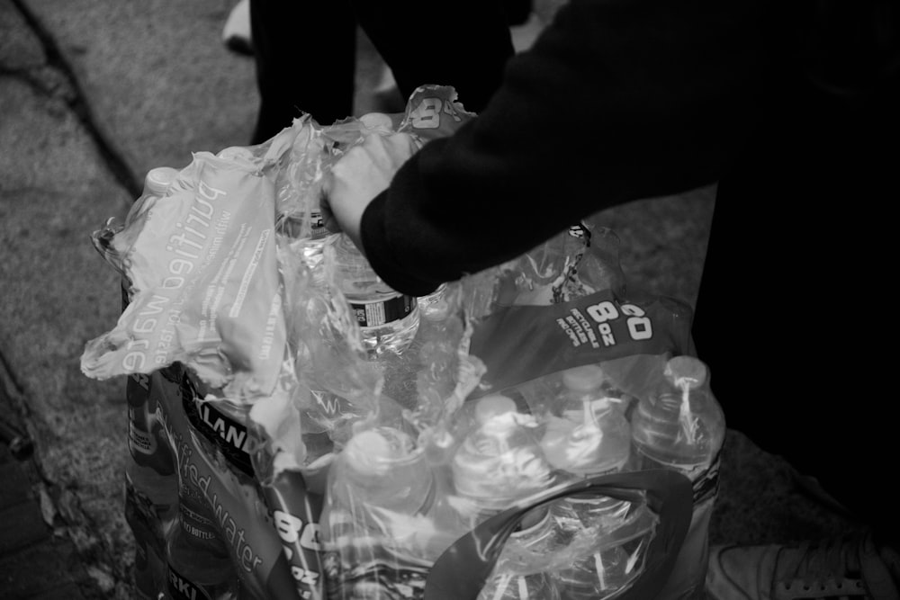 a black and white photo of a person holding a bag of bottled water