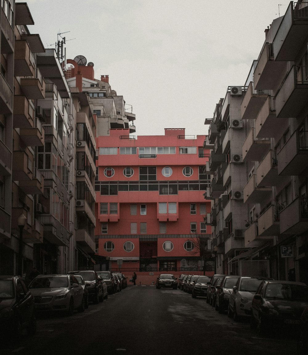 a very tall red building sitting between two rows of parked cars