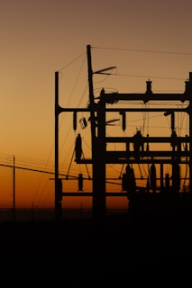 a silhouette of a power line with a sunset in the background