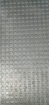 A textured surface made up of rows of repetitive circular patterns, likely part of a metal sheet used for flooring or as an anti-slip surface.