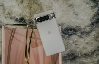 Google Pixel phone resting on a soft white surface with pink highlights.