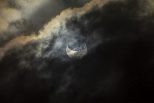 the moon is partially obscured by clouds in the sky