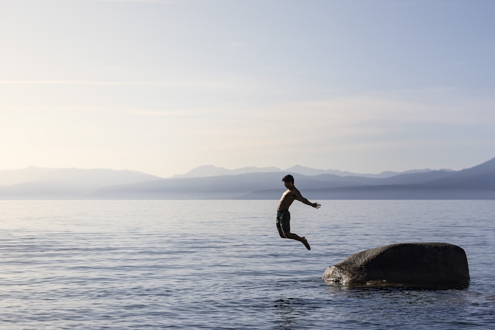 a person jumping off a rock into the water