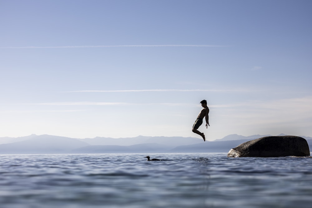 a person jumping off a rock into the water