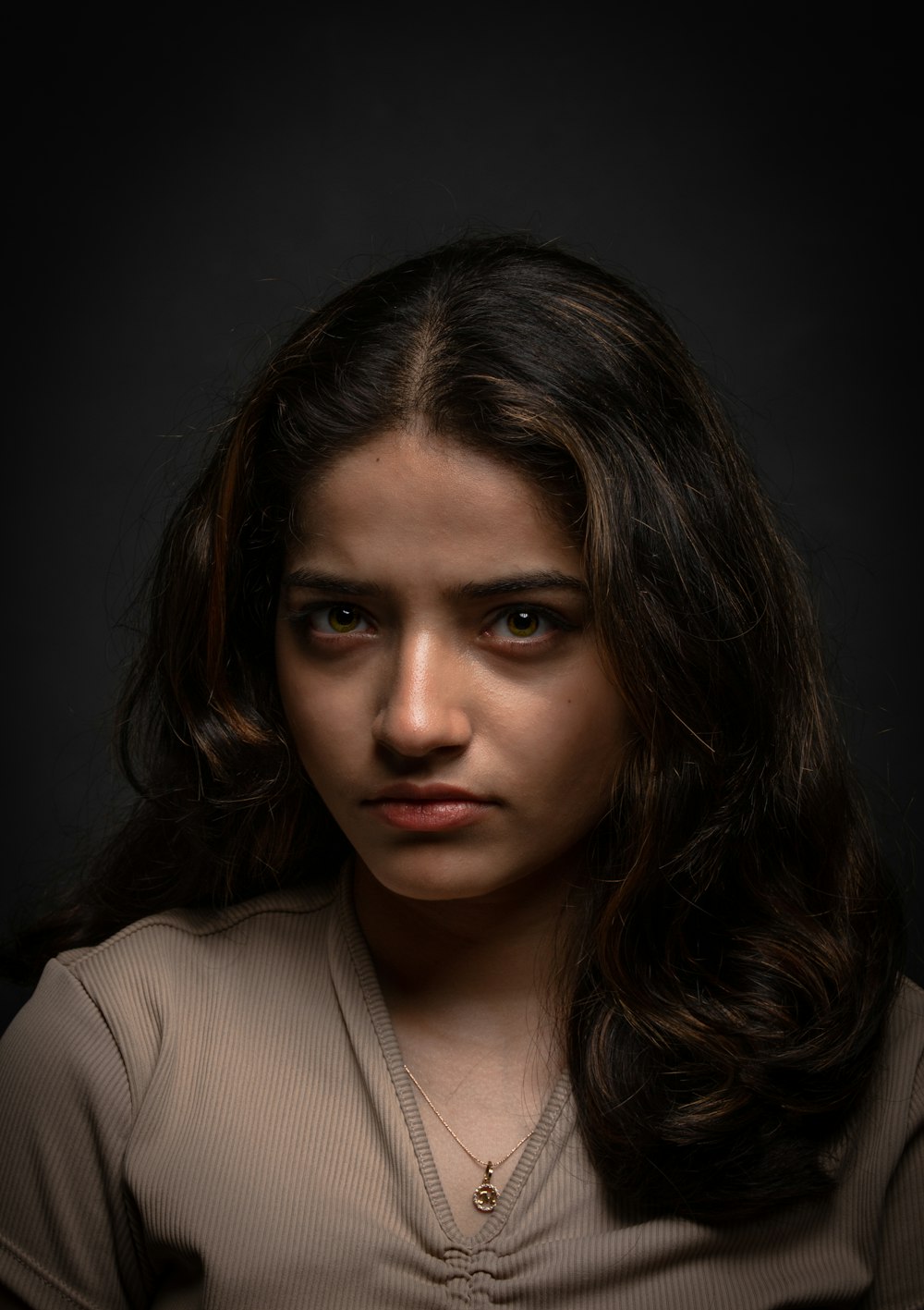 a woman with long dark hair and a brown shirt