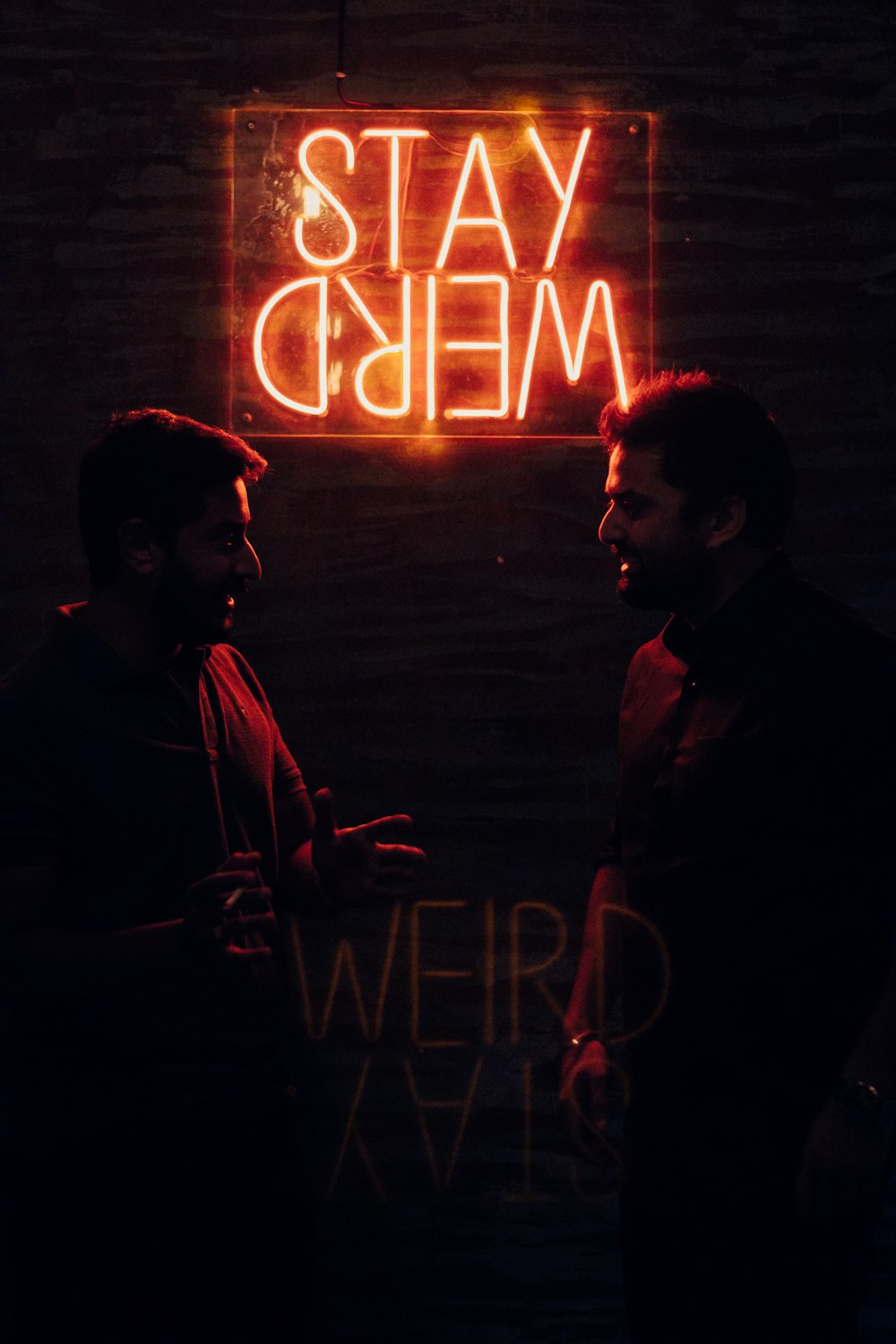 two men standing in front of a neon sign