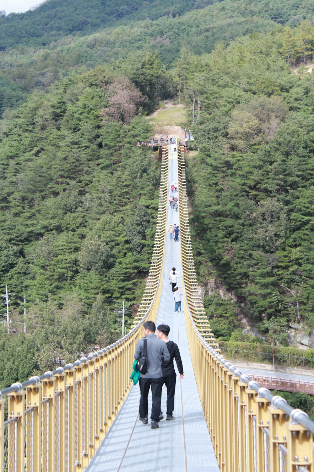 two men walking across a suspension bridge in the mountains