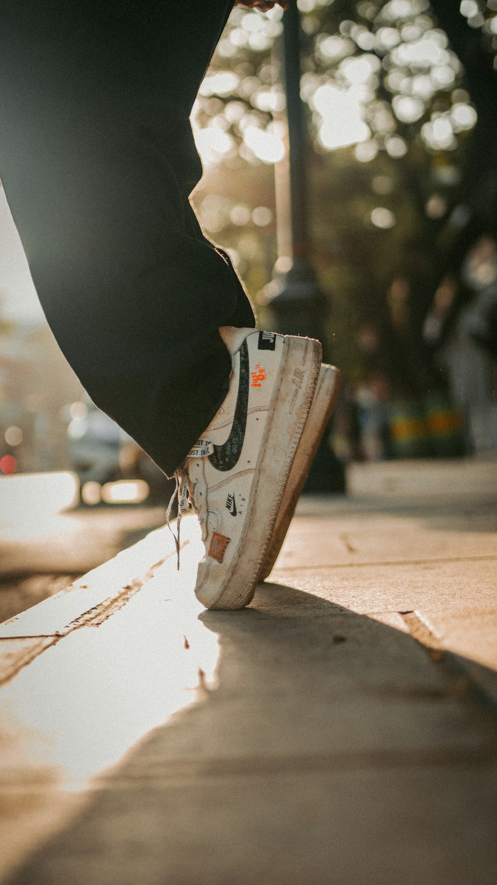 a person standing on a sidewalk with their foot on a skateboard