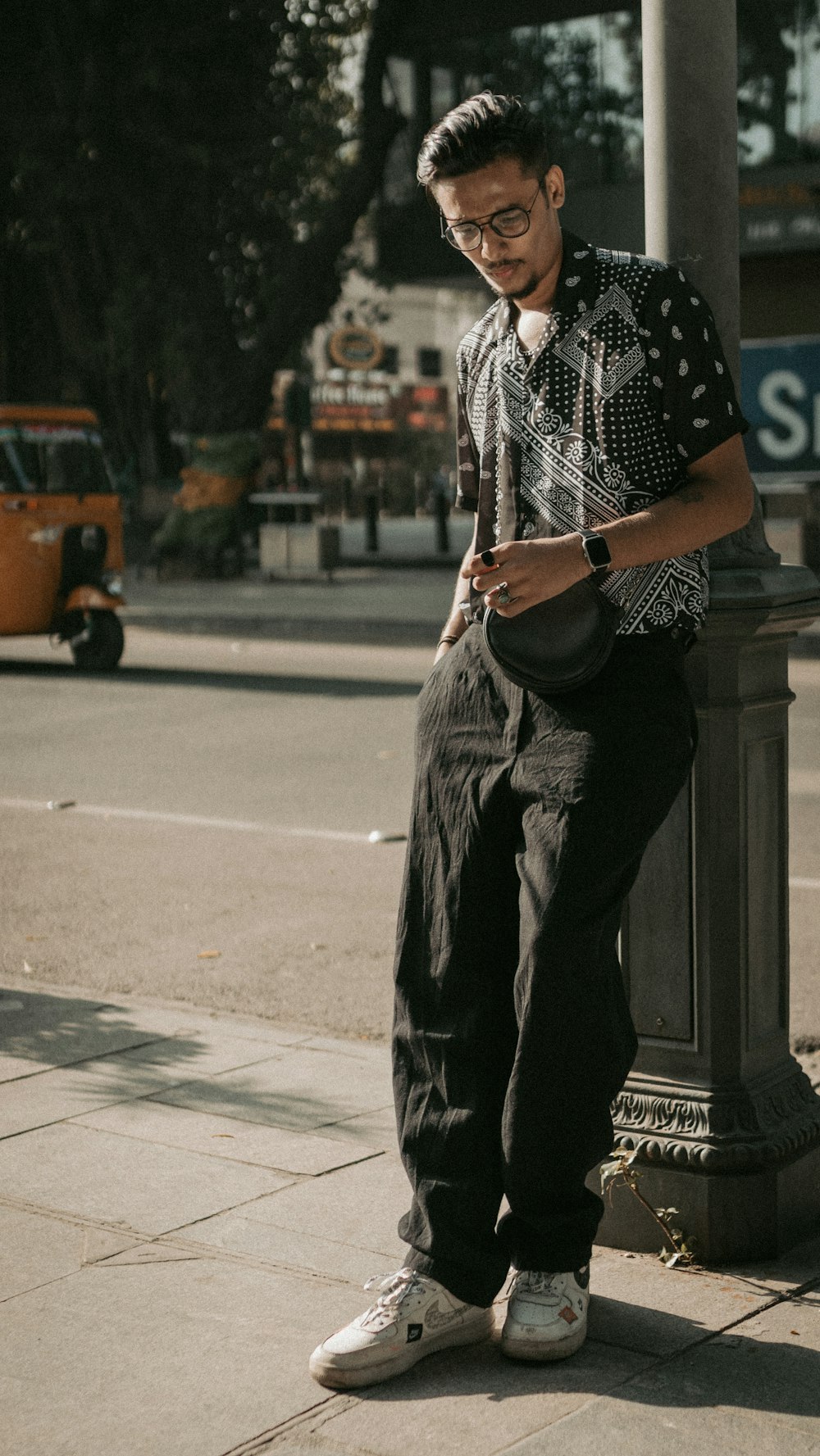 a man sitting on a pole looking at his cell phone