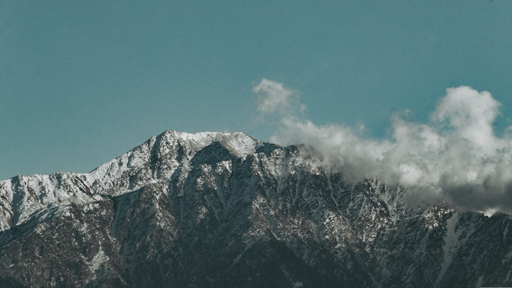 a snow covered mountain range with clouds in the sky