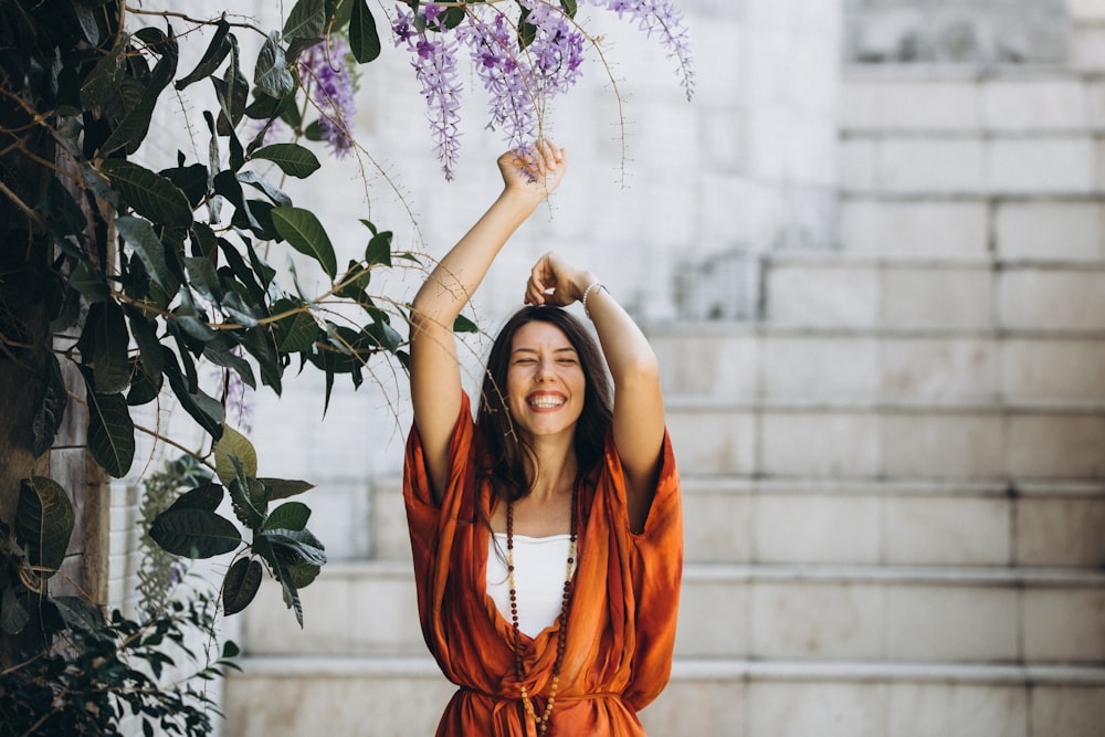 a woman holding a bunch of purple flowers over her head