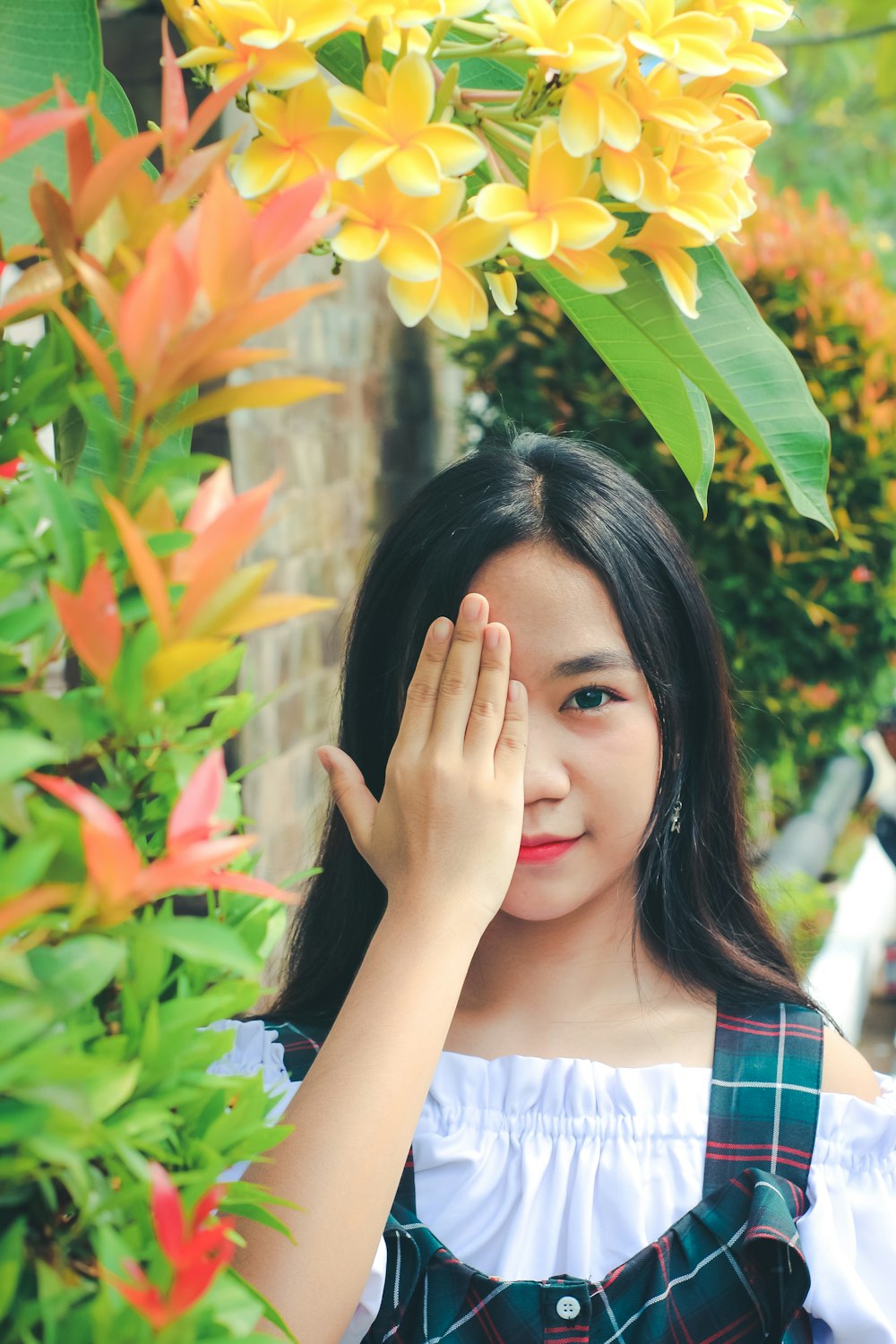 a young girl standing next to a bush of flowers