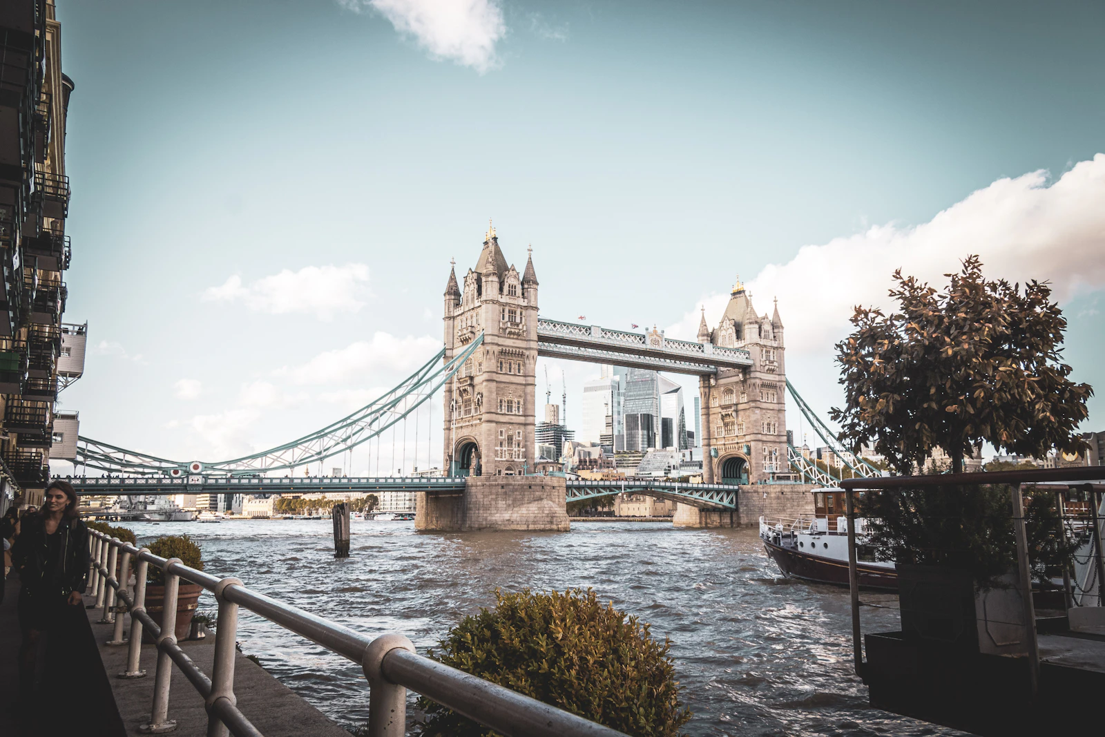 Photograph of Tower Bridge spanning the river, with modern City towers visible between its stone towers.